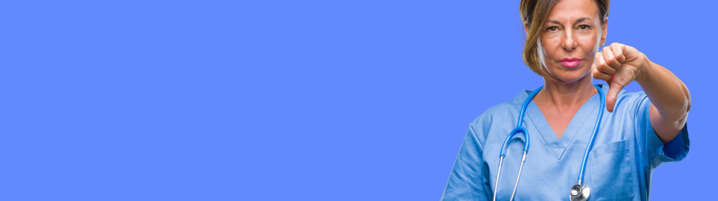 Female nurse in scrubs with a stethoscope giving a thumbs-down gesture against a purple background.